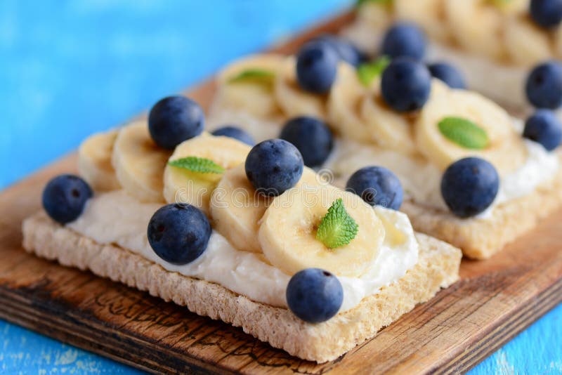 Pain grillé fait maison de pain croustillant avec le fromage blanc, la banane et les baies sur le conseil en bois Idée de sandwic images stock Pain grillé fait maison de pain croustillant avec le fromage blanc, la banane et les baies sur le conseil en bois Idée de sandwic images stock