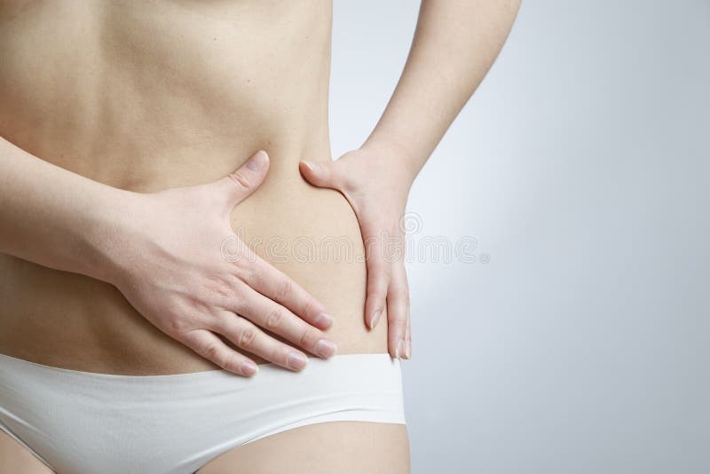 Close Up of Woman in Underwear Holding Stomach in Pain Stock Photo