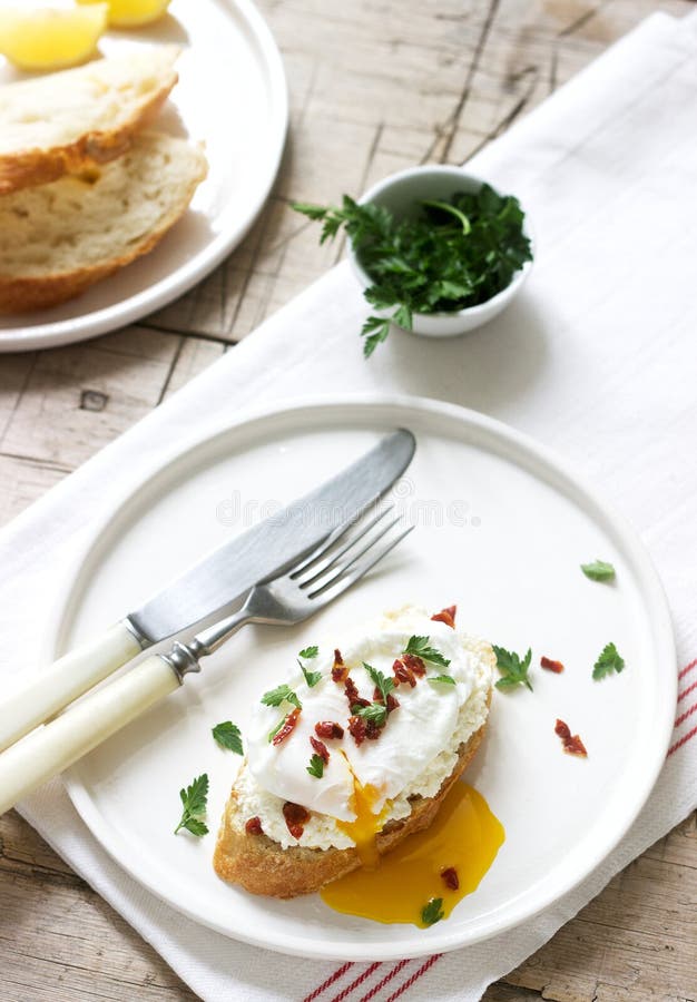 Pains grillés croustillants de baguette avec le fromage blanc, l'oeuf poché et les tomates sèches sur un fond clair photographie stock Pains grillés croustillants de baguette avec le fromage blanc, l'oeuf poché et les tomates sèches sur un fond clair photographie stock