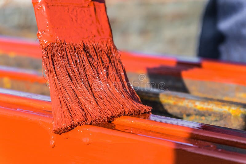 Paint application by brush on metal structures. Protective coating of steel closed profiles with primer iron oxide red royalty free stock photos