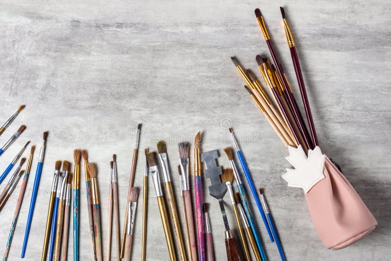Paint brushes in the original gift bag and scattered on the table on a gray background, drawing tools top view, copy space, close-. Up royalty free stock image Paint brushes in the original gift bag and scattered on the table on a gray background, drawing tools top view, copy space, close-. Up royalty free stock image