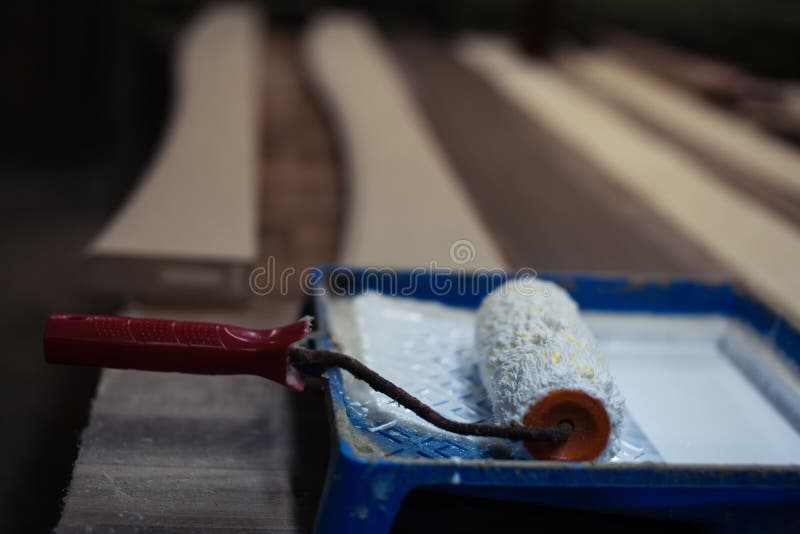 Paint Roller Soiled with White Paint in a Blue Container Stock Photo