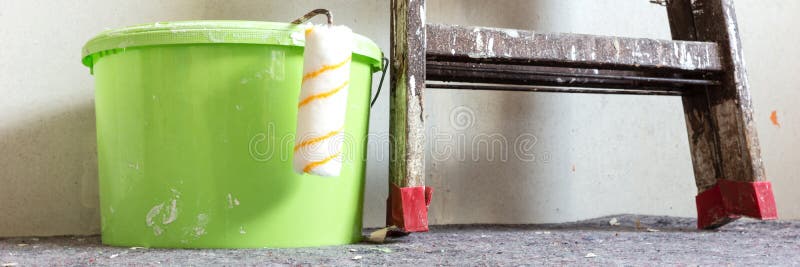 Paint roller, wooden ladder and green plastic bucket. Panorama