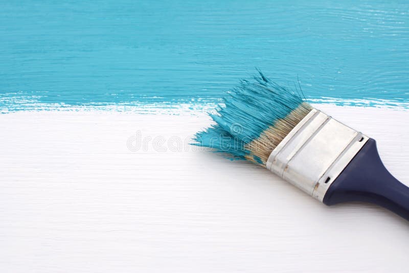 Paintbrush with blue paint, painting over white board