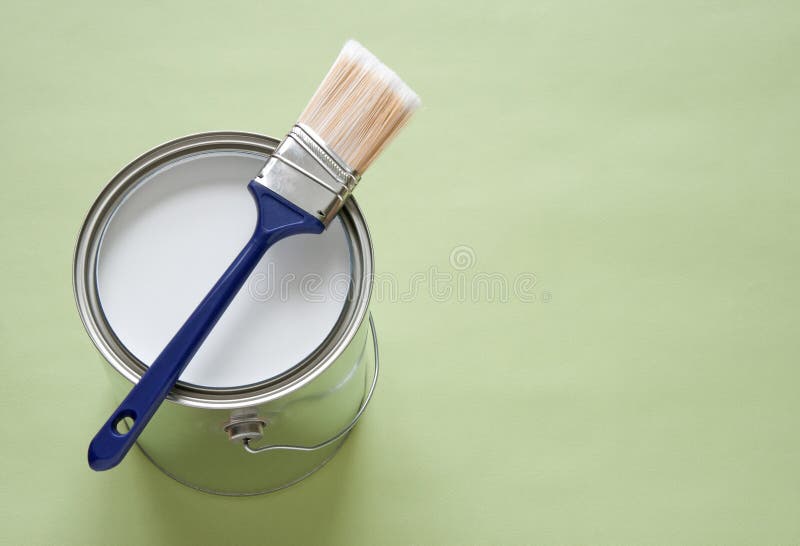 Paintbrush and can of paint on green background