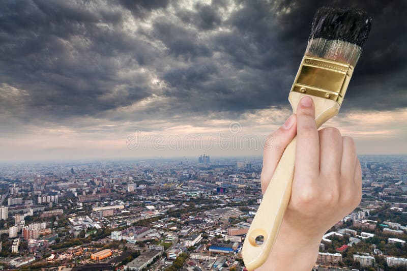 Paintbrush paints storm clouds over dark city