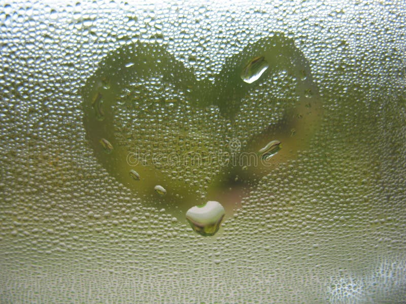 Painted heart on window glass and rain drops