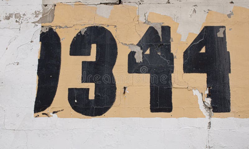 Painted numbers on the old wall with textured dried out crucked paint on the street.