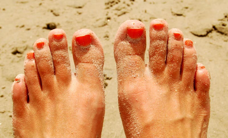 Sandy feet with orange painted toes. Sandy feet with orange painted toes