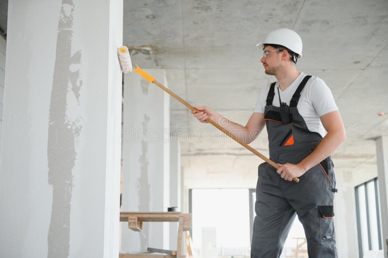 Painter man painting the wall, with paint roller stock photography