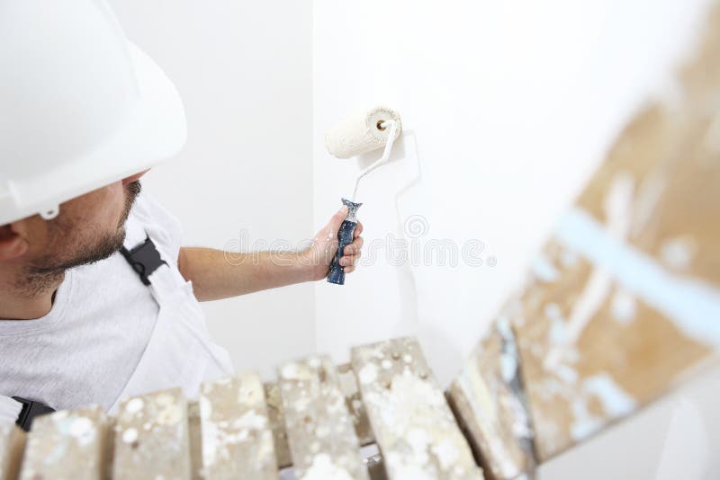 Painter man at work with paint roller, on ladder, wall paintin stock photo
