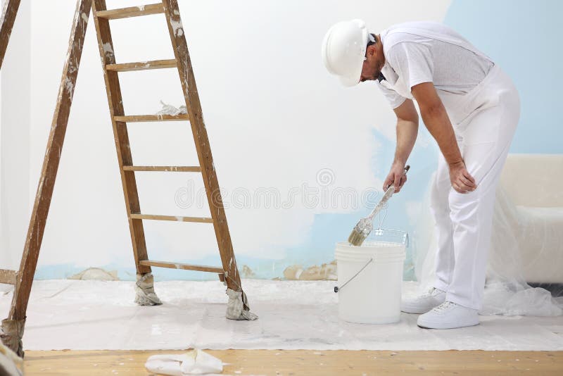 Painter man at work takes the color with paint brush from the bu royalty free stock photo