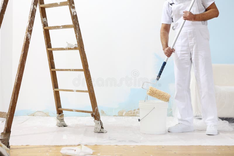 Painter man at work takes the color with paint roller from the b stock photography