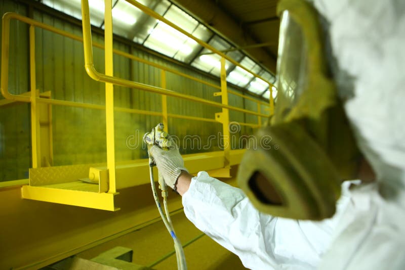 Industrial painting parts. The painter paints the iron element in yellow. royalty free stock photography Industrial painting parts. The painter paints the iron element in yellow. royalty free stock photography