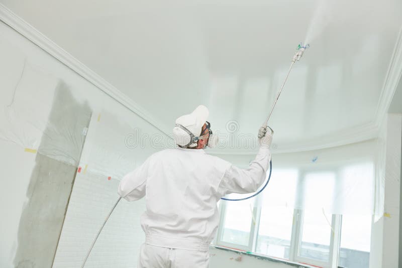 Painter worker with airless painting sprayer covering ceiling surface into white