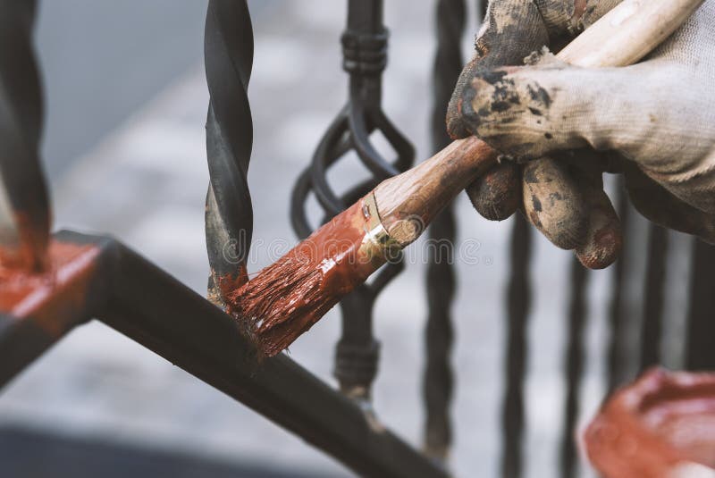 Painting forged railings on the stairs at the entrance of the house. Protection against rust. stock photos Painting forged railings on the stairs at the entrance of the house. Protection against rust. stock photos