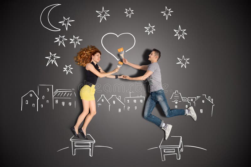 Happy valentines love story concept of a romantic couple standing on a stool and painting a heart in the night sky against chalk drawings background. Happy valentines love story concept of a romantic couple standing on a stool and painting a heart in the night sky against chalk drawings background.