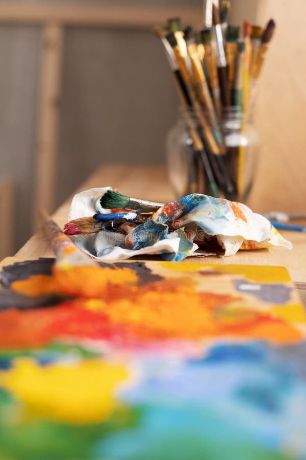 Painting palette and paint brush in glass jar on wooden table or windowsill. Art still life