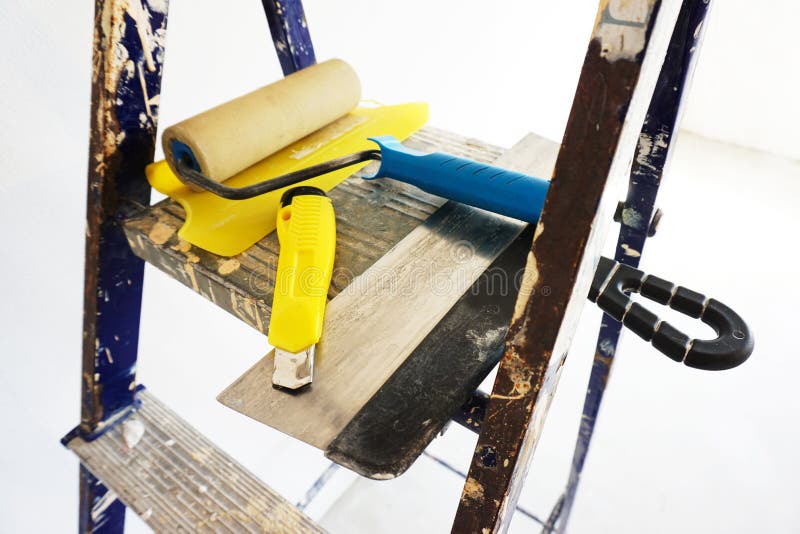 Painting tools lie on a metal stepladder. The concept of replacing wallpaper at home royalty free stock image