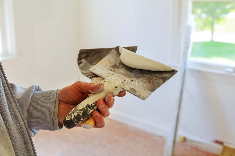 Painting Worker Puttied Wall Using a Paint Spatula Hand. Stock Photo