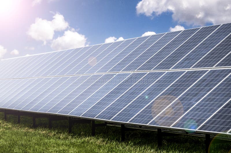 Solar panels in grassy lawn reflecting sunshine with blue skies and clouds. Solar panels in grassy lawn reflecting sunshine with blue skies and clouds.