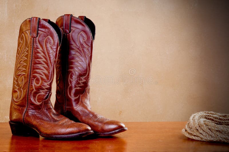 A pair of brown cowboy boots and a coil of rope