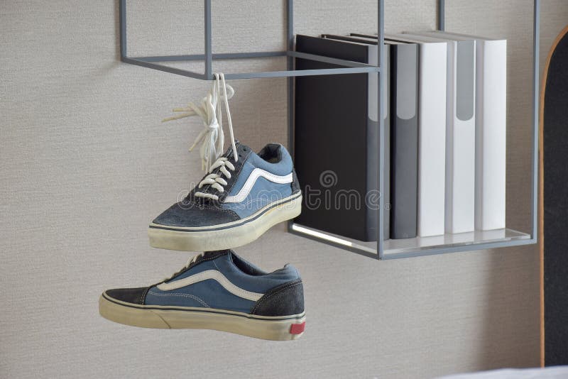 Pair of casual blue sneaker shoes hanging on book shelf