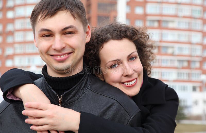 Pair embraces and smiles against building