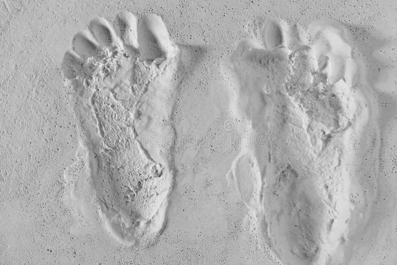 Pair of footprints cast in a white smooth textured sandy surface - A cast pair of footprints in plaster. Pair of footprints cast in a white smooth textured sandy surface - A cast pair of footprints in plaster