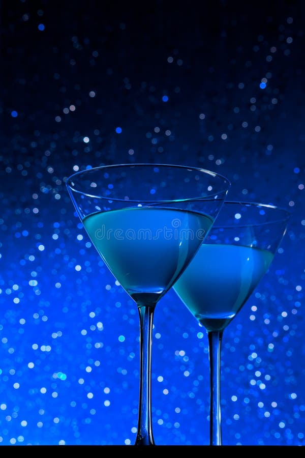 Two Glasses of Blue Cocktail on Dark Green Tint Light Bokeh Stock Photo