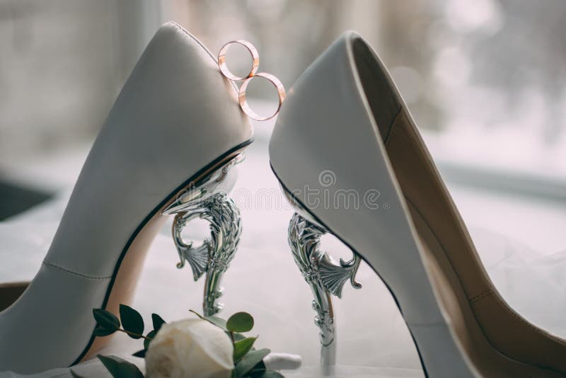 A pair of white wedding shoes with rings on a stool. stock photo A pair of white wedding shoes with rings on a stool. stock photo