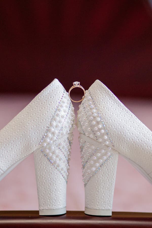 A pair of white wedding shoes with rings on a stool stock image A pair of white wedding shoes with rings on a stool stock image