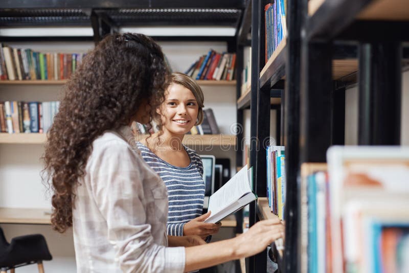 Look library. Девушка около книжной полки. Две девочки около книжной полки. Девушка у полки с книгами. Две девочки около книжной полки читают книги.