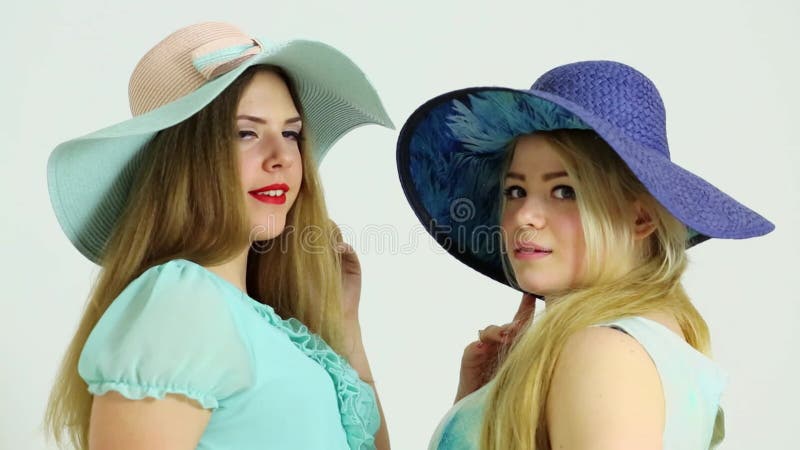 Paire de jeunes femmes attrayantes en gros chapeaux sourire banque de vidéos