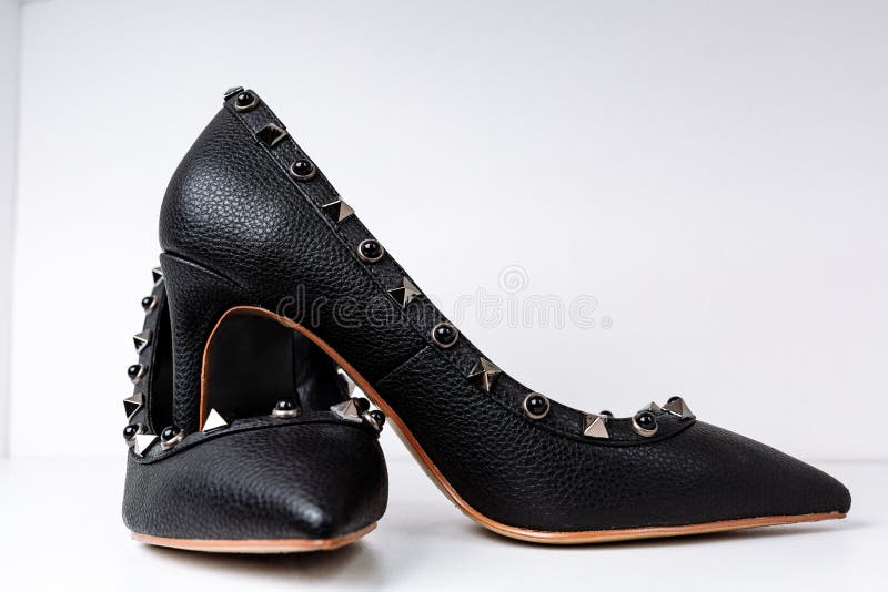 Paires de chaussures ? talons hauts noires avec les orteils aigus, d?cor?es des insertions en m?tal contre une ?tag?re dans le ma photos libres de droits Paires de chaussures ? talons hauts noires avec les orteils aigus, d?cor?es des insertions en m?tal contre une ?tag?re dans le ma photos libres de droits