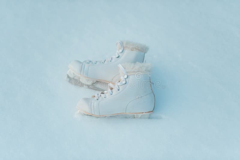 Paires de patins de glace blancs à l'arrière-plan de neige image stock Paires de patins de glace blancs à l'arrière-plan de neige image stock