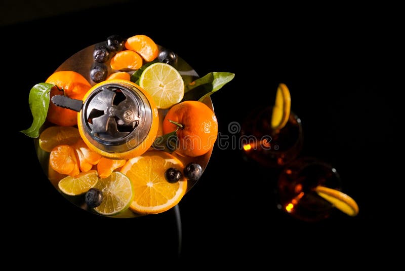 Pair of glasses with alcoholic drink beverage wine cocktail and hookah with fruits black background isolated. Pair of glasses with alcoholic drink beverage wine cocktail and hookah with fruits black background isolated