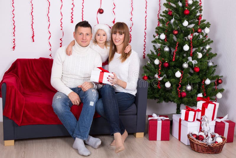 Pais alegres com a filha que senta-se perto da árvore de Natal em ho imagens de stock royalty free Pais alegres com a filha que senta-se perto da árvore de Natal em ho imagens de stock royalty free