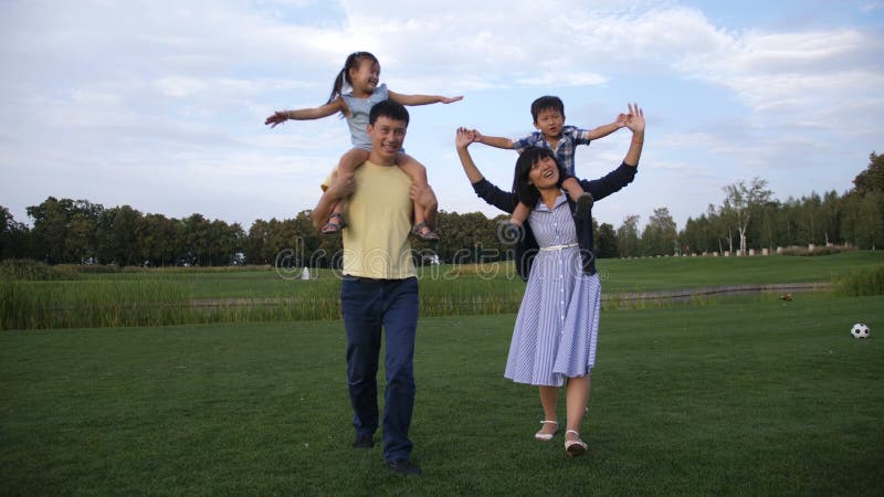 Pais asiáticos alegres que levam crianças em ombros