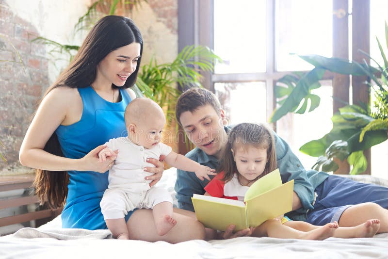 Pais lendo o livro para seus filhos fotografia de stock Pais lendo o livro para seus filhos fotografia de stock