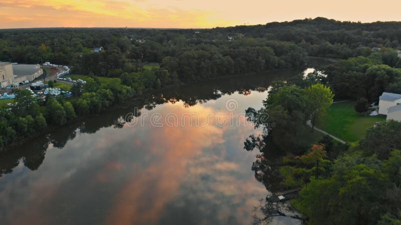 Paisagem colorida do rio perto de uma floresta sob um céu bonito com as nuvens brilhantes durante o por do sol