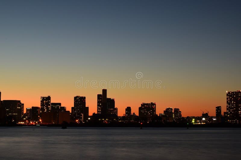 Paisagem urbana em torno da água da baía no crepúsculo imagens de stock Paisagem urbana em torno da água da baía no crepúsculo imagens de stock