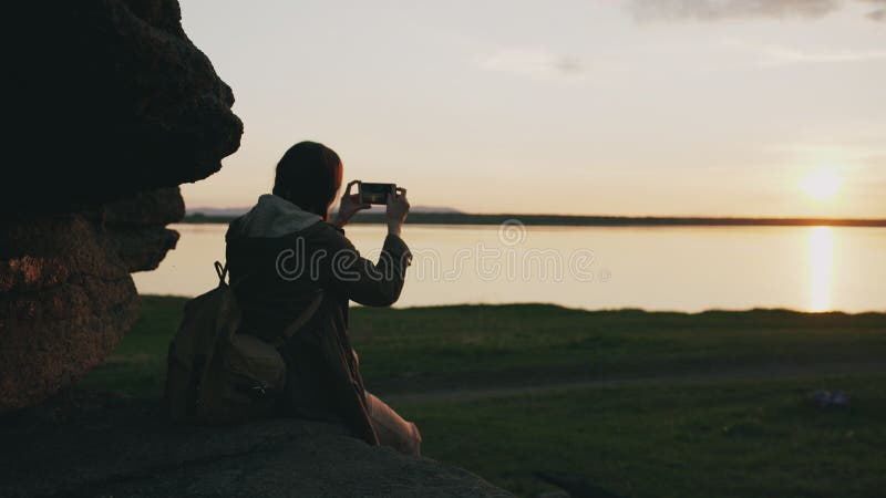 Paisaje de fotografía del backpacker turístico joven de la mujer en su cámara del smartphone después de caminar en roca en la pue fotos de archivo libres de regalías Paisaje de fotografía del backpacker turístico joven de la mujer en su cámara del smartphone después de caminar en roca en la pue fotos de archivo libres de regalías