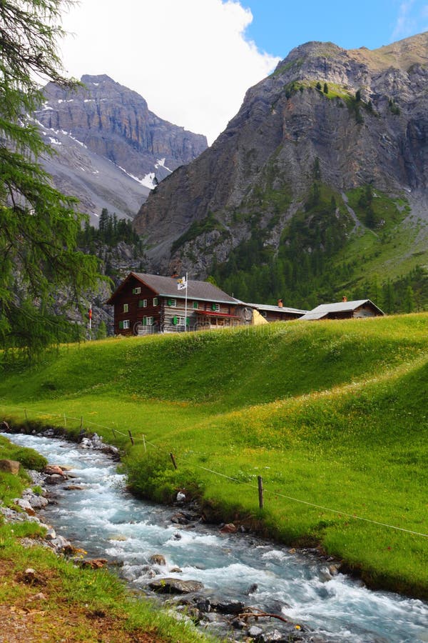 Summer mountain landscape with chalet on green meadow and stream in the foreground, Sertig Dorfli, Davos, Switzerland. Summer mountain landscape with chalet on green meadow and stream in the foreground, Sertig Dorfli, Davos, Switzerland