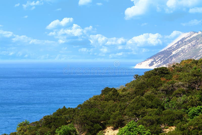 Paisaje de la orilla de mar - montañas verdes en el fondo azul de cielo nublado fotos de archivo Paisaje de la orilla de mar - montañas verdes en el fondo azul de cielo nublado fotos de archivo