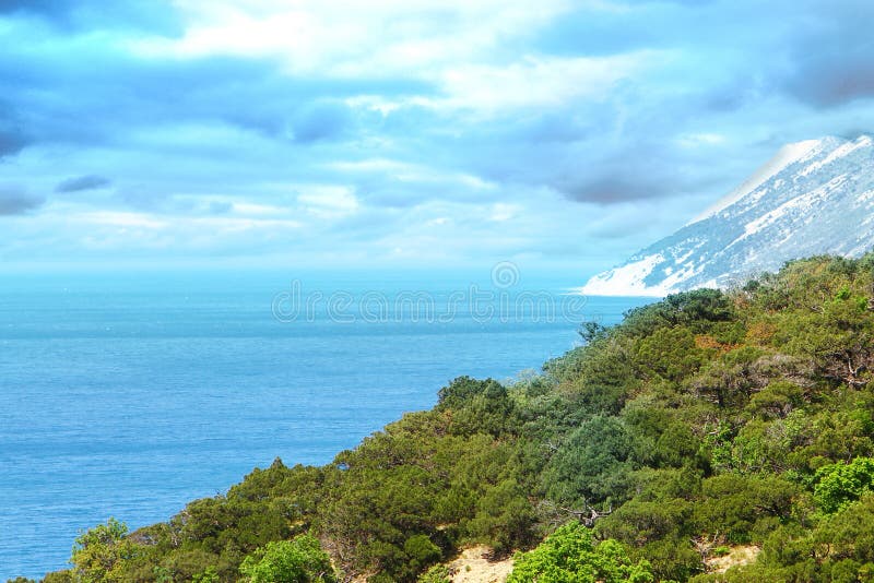 Paisaje de la orilla de mar - montañas verdes en el fondo pesado azul del cielo nublado imagen de archivo libre de regalías Paisaje de la orilla de mar - montañas verdes en el fondo pesado azul del cielo nublado imagen de archivo libre de regalías