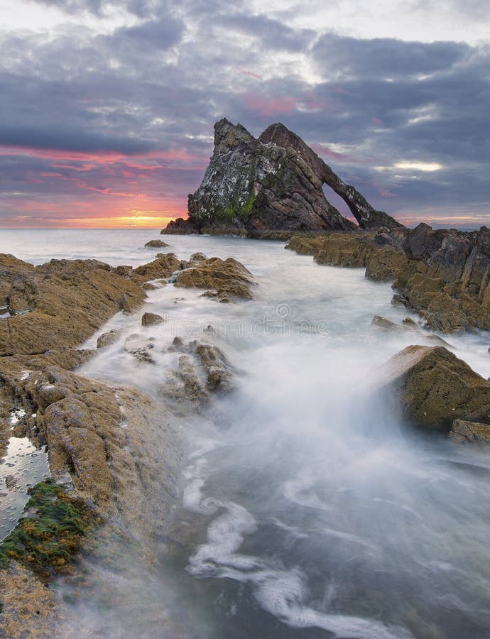 Paisaje de la salida del sol de la roca del arco-fidle en la costa de Escocia en ma?ana nublada imagenes de archivo Paisaje de la salida del sol de la roca del arco-fidle en la costa de Escocia en ma?ana nublada imagenes de archivo