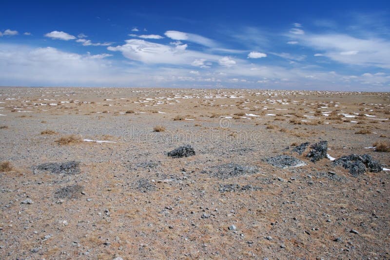 Paisaje del desierto de Gobi con los puntos nevosos, las arenas beige y las rocas negras en un día soleado, Mongolia imagenes de archivo Paisaje del desierto de Gobi con los puntos nevosos, las arenas beige y las rocas negras en un día soleado, Mongolia imagenes de archivo