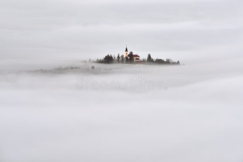 Paisaje hermoso de Eslovenia con la niebla y la iglesia por la mañana fotos de archivo libres de regalías Paisaje hermoso de Eslovenia con la niebla y la iglesia por la mañana fotos de archivo libres de regalías