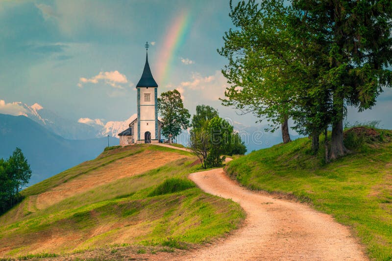 Paisaje idílico del arco iris con la iglesia de Primoz del santo, cerca de Jamnik, Eslovenia